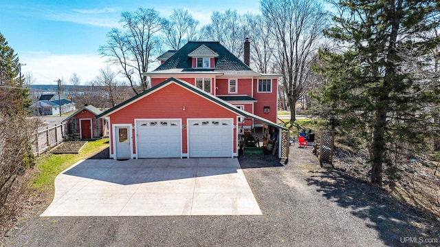 view of front of home featuring driveway, a chimney, and a garage