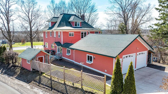 exterior space with a chimney, fence, an outdoor structure, a garage, and a storage unit