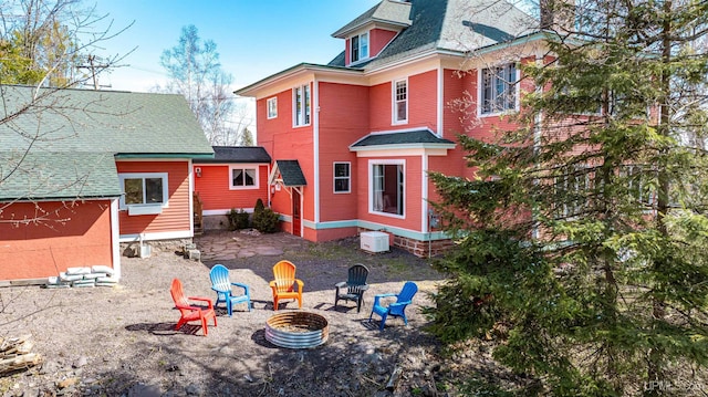 rear view of house featuring a fire pit and roof with shingles