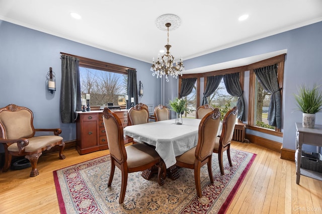 dining space featuring crown molding, light wood-type flooring, and a chandelier