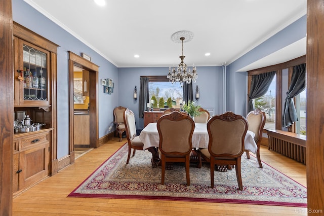 dining space featuring an inviting chandelier, crown molding, baseboards, and light wood finished floors