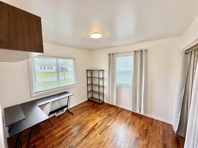unfurnished office featuring baseboards and wood finished floors