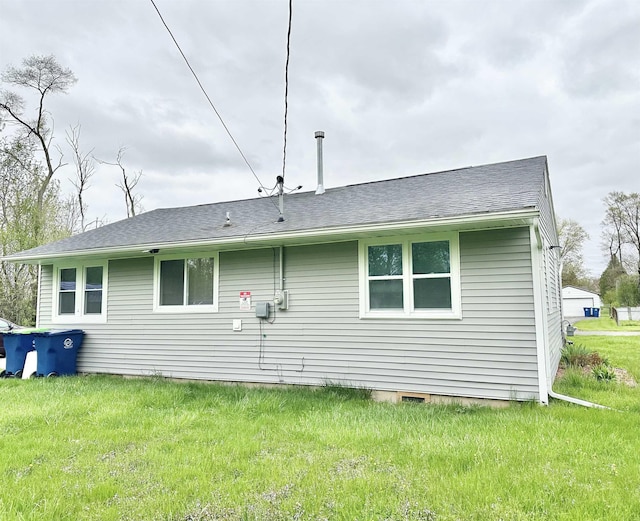 back of house with a shingled roof, crawl space, and a lawn