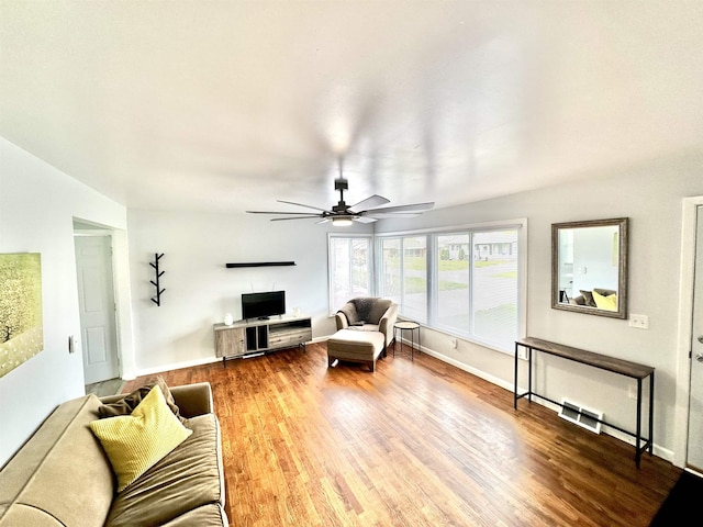 living area with baseboards, a ceiling fan, and wood finished floors