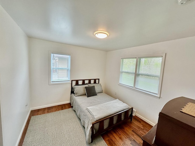 bedroom featuring wood finished floors, baseboards, and multiple windows