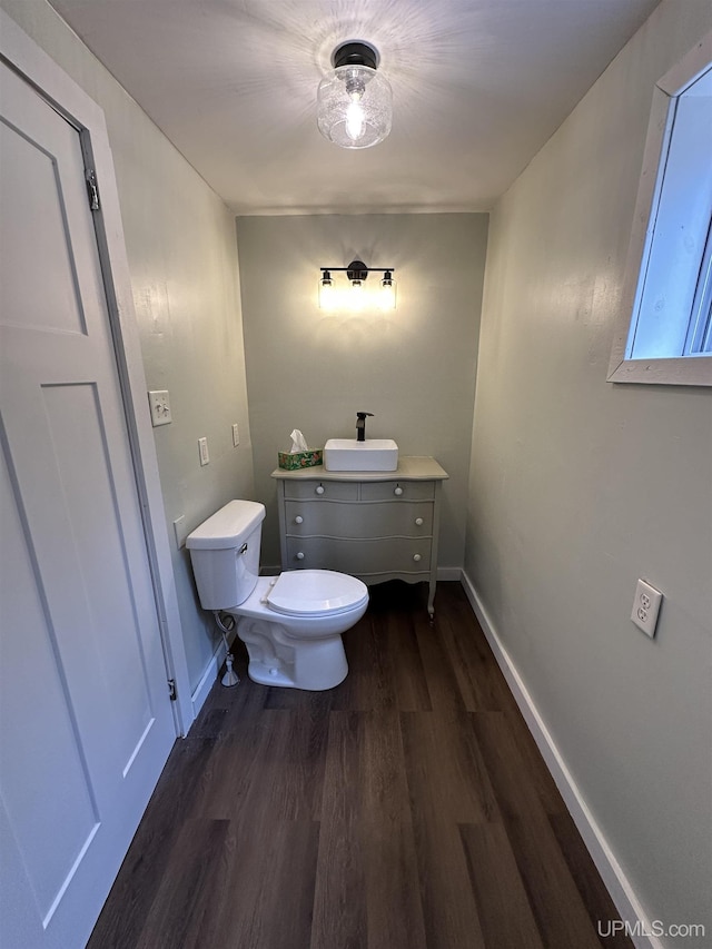 bathroom featuring vanity, toilet, baseboards, and wood finished floors