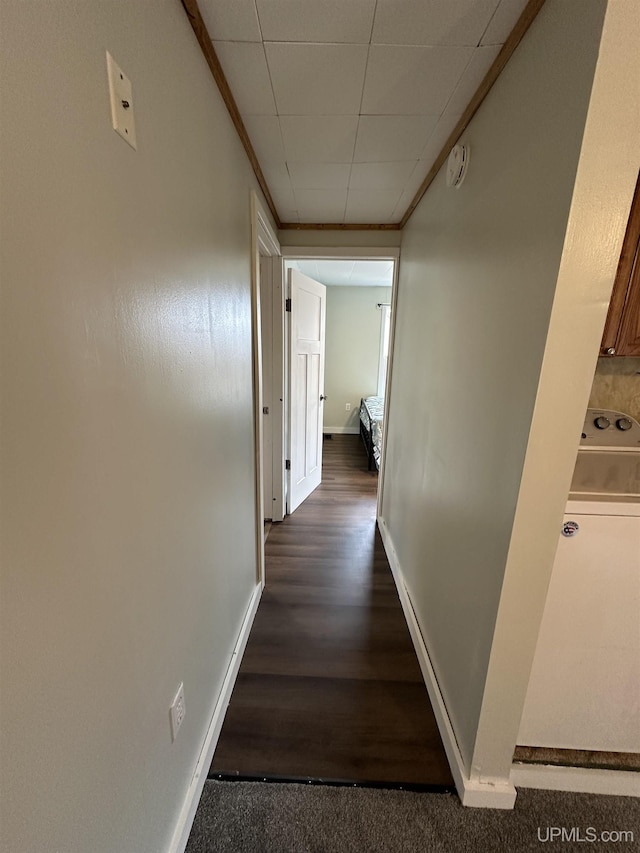 hallway with a drop ceiling, baseboards, and dark wood finished floors