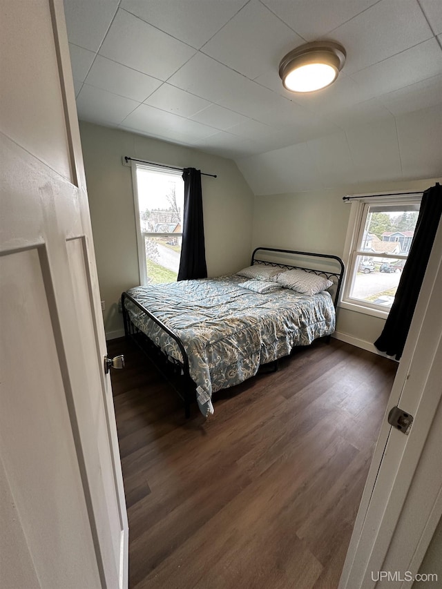 bedroom with baseboards, dark wood finished floors, and vaulted ceiling