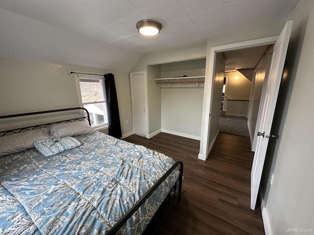 bedroom with baseboards, dark wood-style flooring, a closet, and vaulted ceiling