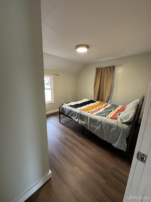 bedroom with baseboards, lofted ceiling, and dark wood-style floors