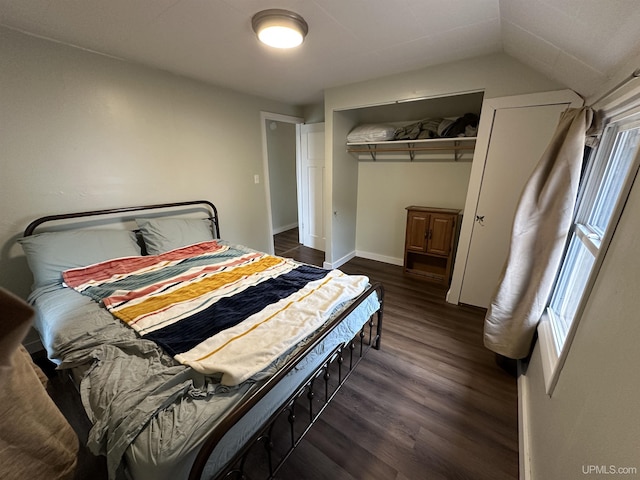 bedroom featuring a closet, baseboards, lofted ceiling, and dark wood-style floors