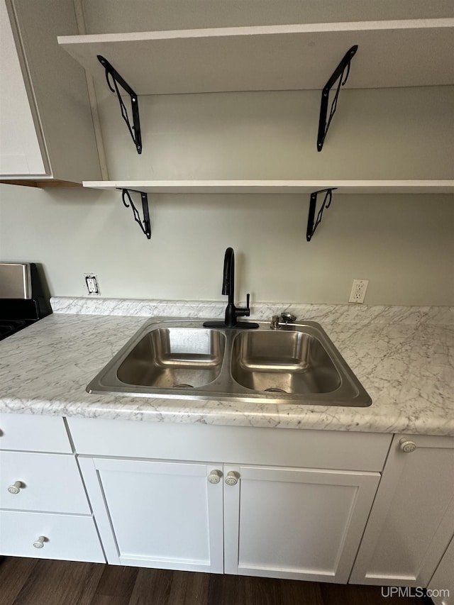 kitchen featuring a sink, open shelves, wood finished floors, light countertops, and white cabinets