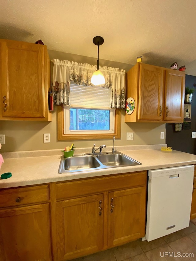 kitchen with light countertops, dark tile patterned floors, a sink, and white dishwasher