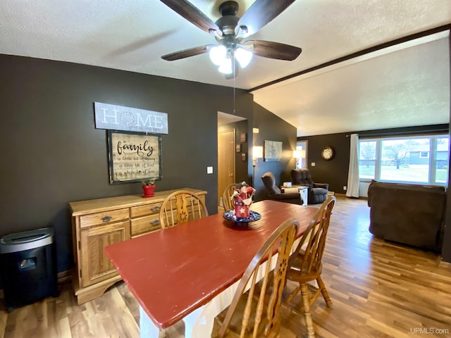dining room featuring vaulted ceiling, light wood finished floors, baseboards, and ceiling fan