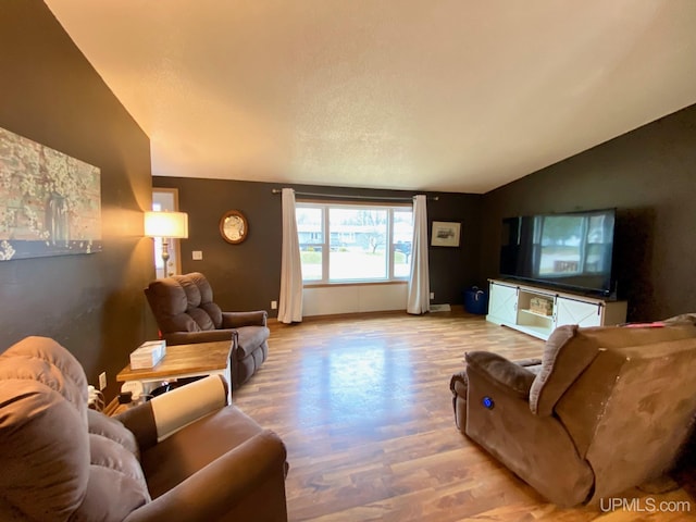 living room with baseboards, wood finished floors, and vaulted ceiling