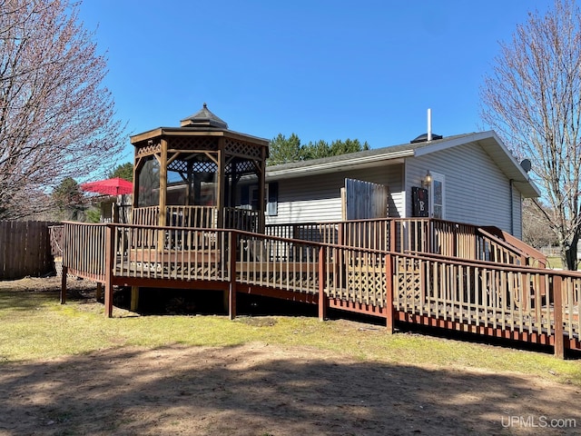 rear view of property featuring a gazebo, a deck, and fence