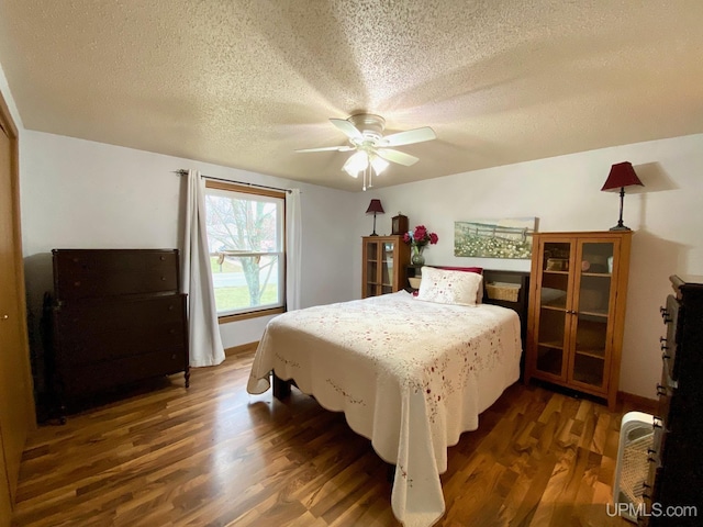 bedroom with dark wood finished floors, ceiling fan, and a textured ceiling