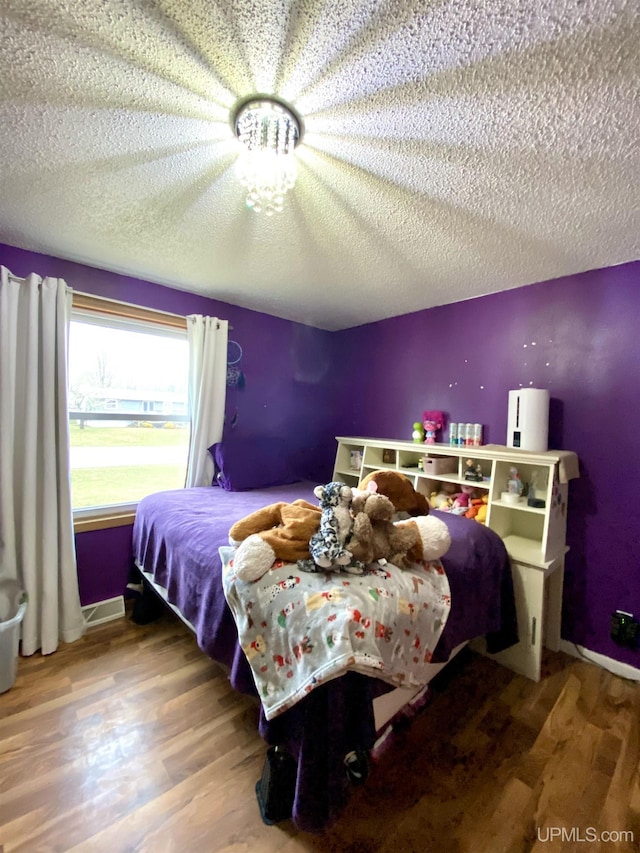 bedroom with a textured ceiling, baseboards, and wood finished floors