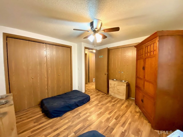 unfurnished bedroom with a textured ceiling, light wood-style flooring, and ceiling fan