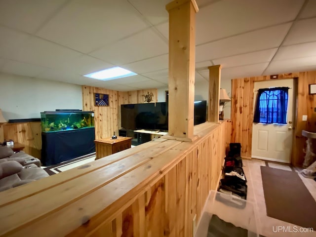 living room with wooden walls, a dry bar, and a drop ceiling