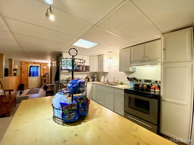 kitchen featuring stainless steel electric range oven, a drop ceiling, a sink, and under cabinet range hood