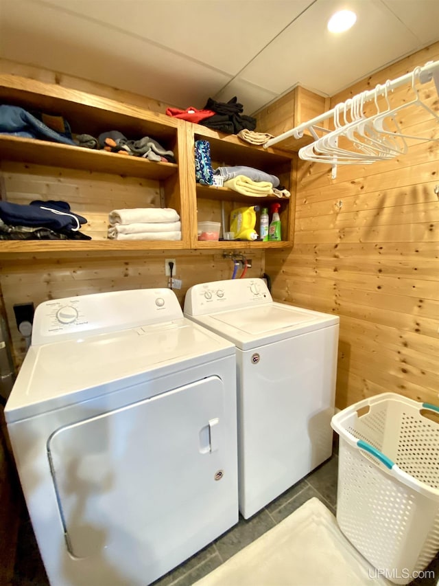 clothes washing area with laundry area, washer and clothes dryer, and wood walls