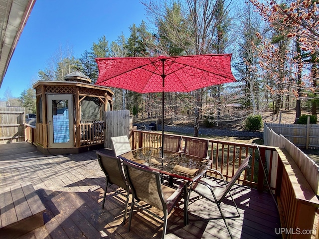 wooden terrace with a gazebo, outdoor dining area, and fence