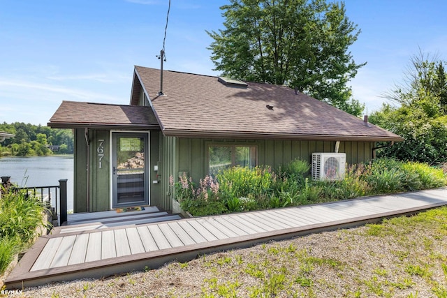 rear view of house with a shingled roof, board and batten siding, a deck, and ac unit