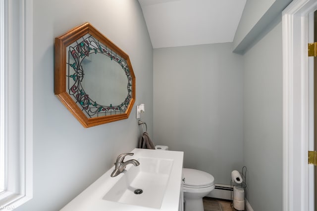 half bathroom featuring vaulted ceiling, vanity, toilet, and baseboard heating