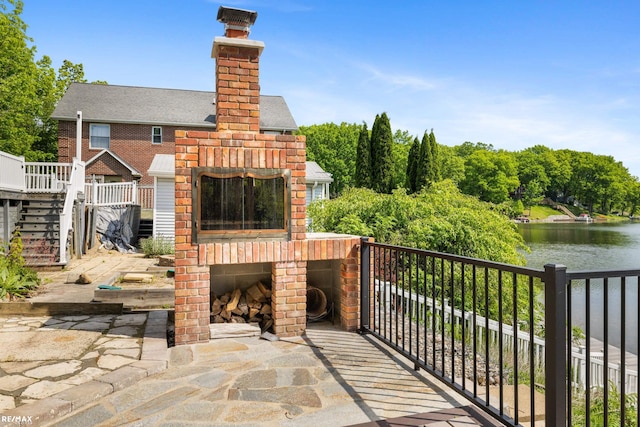 view of patio / terrace featuring a water view and an outdoor brick fireplace