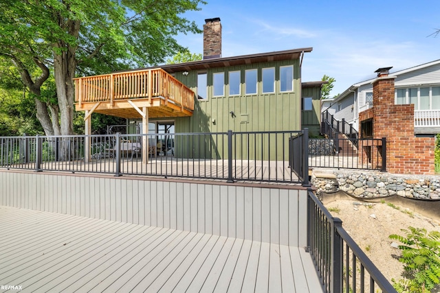 rear view of property with fence private yard, a wooden deck, a chimney, and board and batten siding