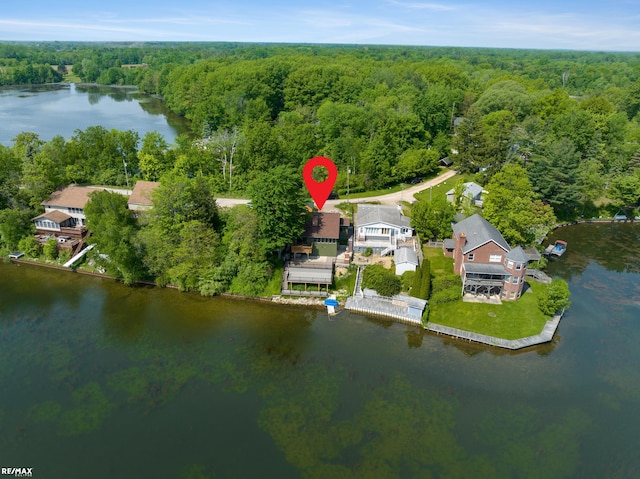 birds eye view of property with a wooded view and a water view