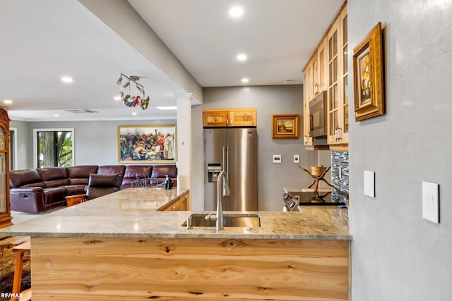 kitchen featuring a sink, recessed lighting, glass insert cabinets, light stone countertops, and appliances with stainless steel finishes