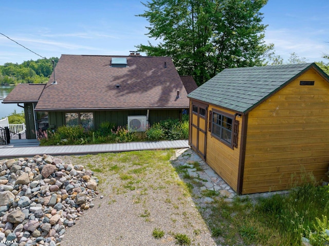 exterior space featuring board and batten siding, an outdoor structure, roof with shingles, and a deck
