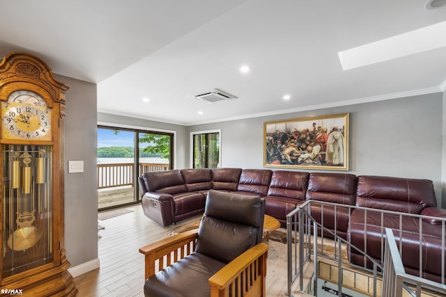 living area featuring crown molding, light wood-style flooring, visible vents, and a skylight
