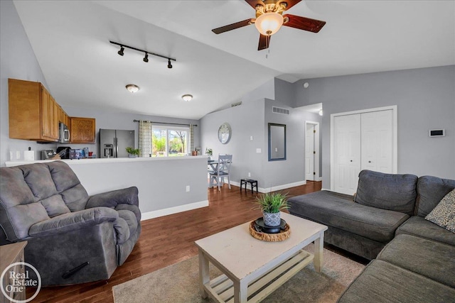 living room with a ceiling fan, vaulted ceiling, visible vents, rail lighting, and wood finished floors