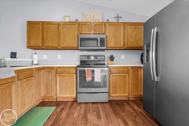 kitchen with vaulted ceiling, dark wood finished floors, light countertops, and appliances with stainless steel finishes