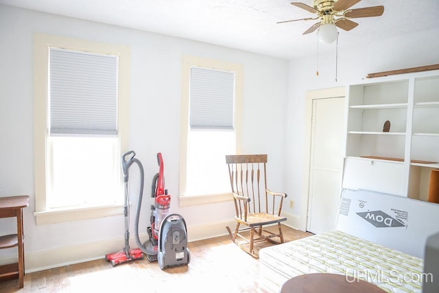 interior space featuring baseboards, a ceiling fan, a healthy amount of sunlight, and wood finished floors