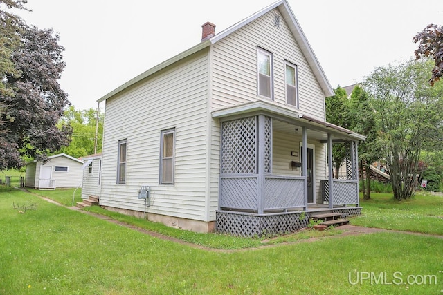 view of home's exterior with a porch, a chimney, and a lawn