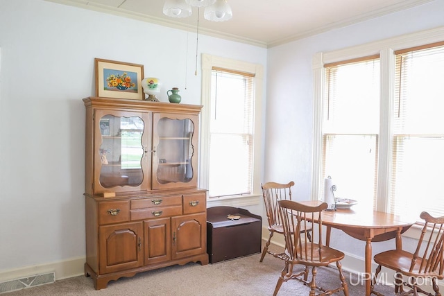 dining room with baseboards, light carpet, crown molding, and visible vents