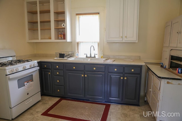 kitchen with a sink, open shelves, white cabinetry, light countertops, and white range with gas stovetop