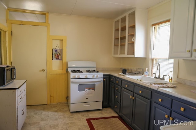 kitchen featuring gas range gas stove, light countertops, stainless steel microwave, and a sink