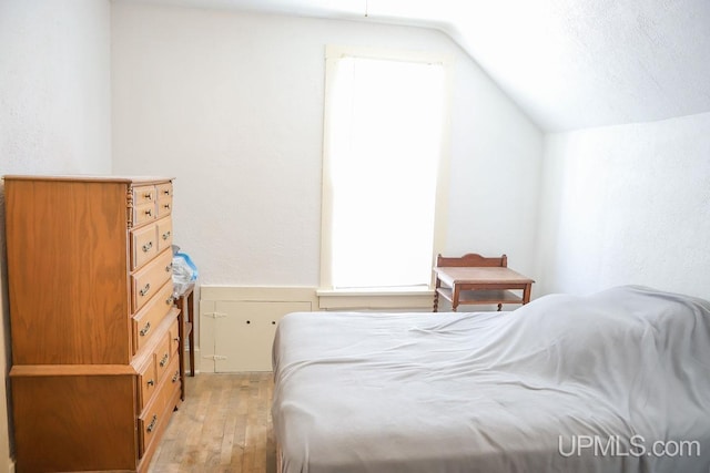 bedroom featuring lofted ceiling and light wood-style floors
