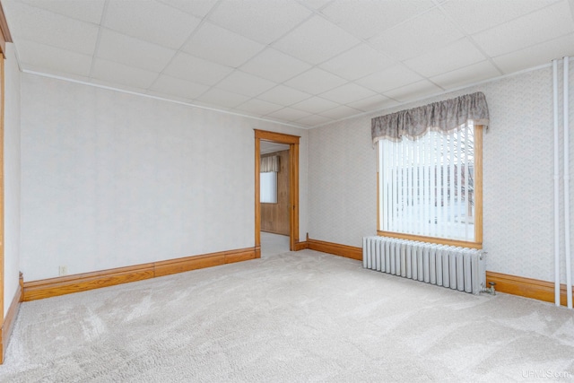 carpeted empty room with radiator, wallpapered walls, a drop ceiling, and baseboards