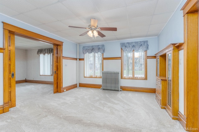 interior space featuring a ceiling fan, light carpet, radiator heating unit, and plenty of natural light