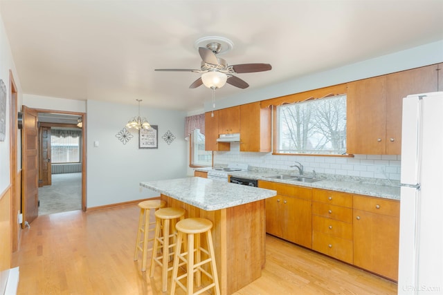 kitchen featuring a sink, white appliances, ceiling fan with notable chandelier, under cabinet range hood, and backsplash