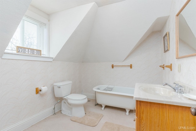 bathroom featuring toilet, vanity, a freestanding bath, and wallpapered walls