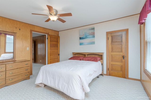 carpeted bedroom with multiple windows, wooden walls, and ceiling fan