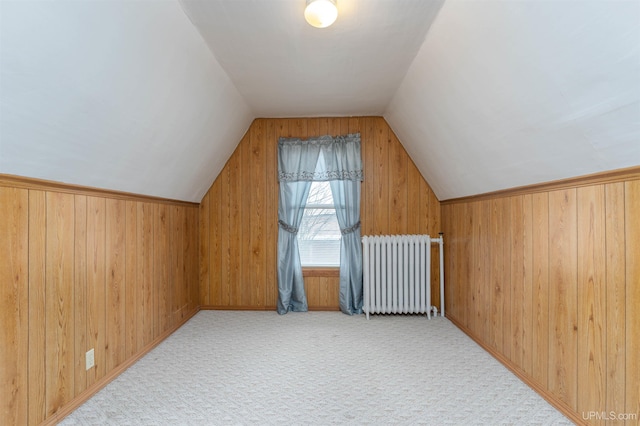 bonus room with vaulted ceiling, wooden walls, carpet, and radiator heating unit