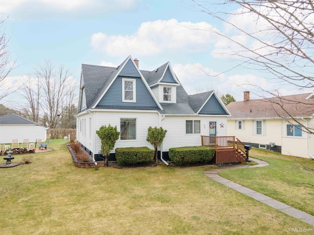 rear view of property with a yard, a deck, roof with shingles, and a chimney